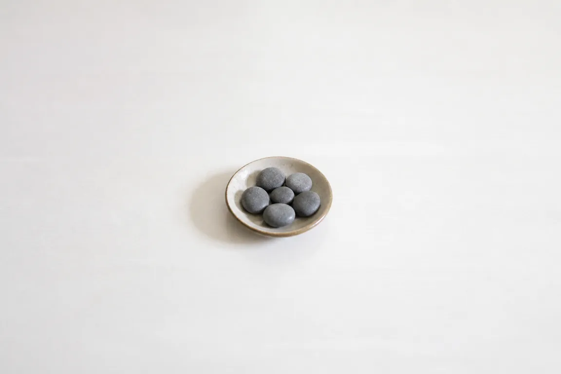 Five river stones in a tiny dish on an empty table