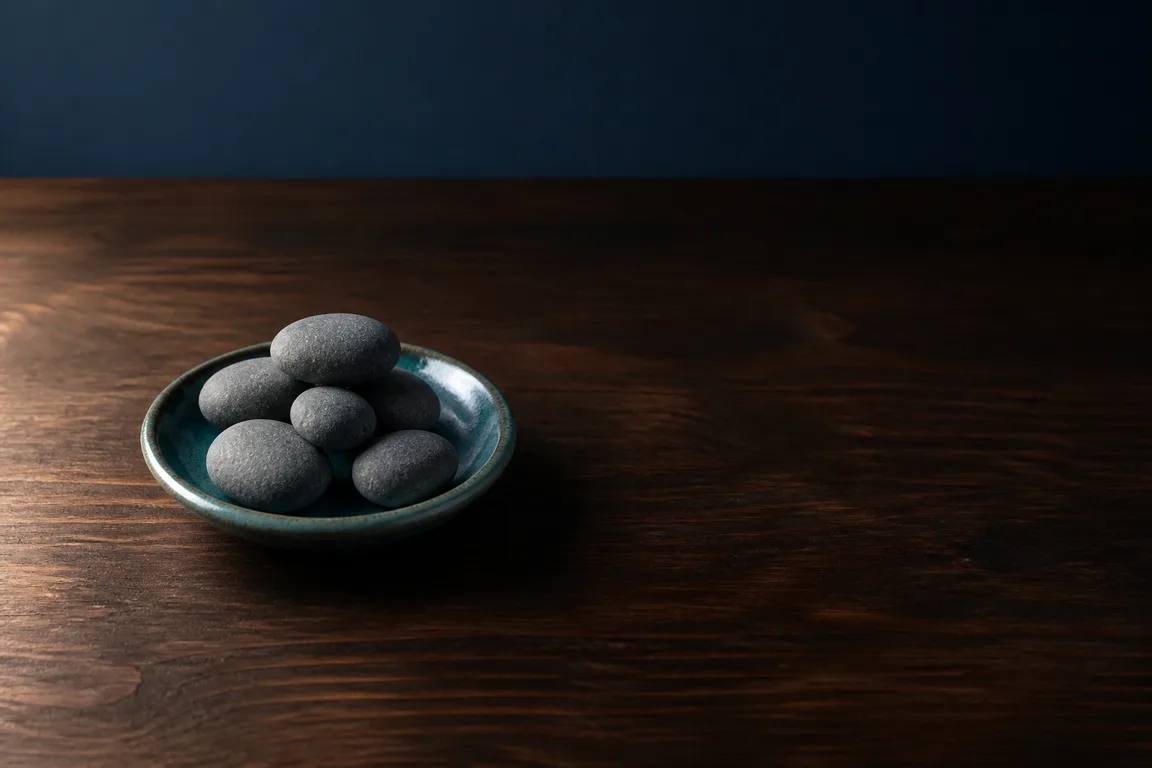 Five river stones in a tiny dish on a dark walnut table